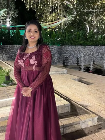 The same client in her custom wine-colored gown, pictured in a different setting. The sheer sleeves and butterfly motifs on the bodice are clearly visible here.