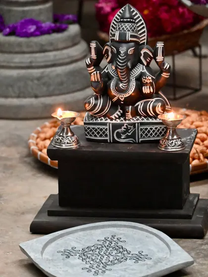A close-up of a reclining Ganesha statue, its form and texture enhanced by the gentle touch of a dancer during a festive celebration.