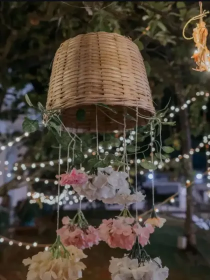 A creative hanging decoration made from a wicker basket and cascading fresh flowers, adding a touch of rustic charm to an outdoor event.