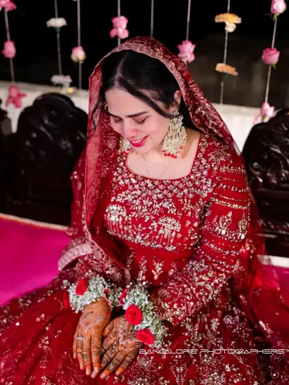 A candid shot of the bride, her face lit with a gentle smile. The rich red of her outfit and the soft focus create a warm and intimate bridal portrait.