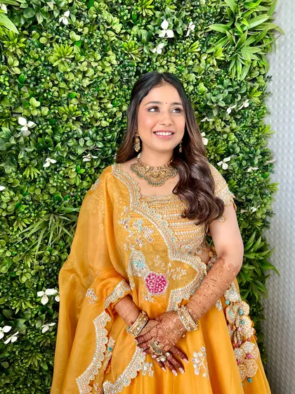 The complete look against a beautiful green backdrop. The yellow lehenga and golden makeup tones create a stunning, sunny vibe.