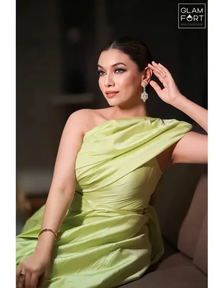 A candid, thoughtful pose. The soft lighting highlights the cheekbones and the subtle shimmer on the skin, creating a very sophisticated and polished look.