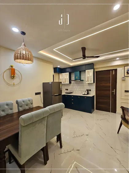 An open-plan layout connecting the dining area and kitchen in our Rishikesh project. The design uses a consistent color scheme and flooring to create a seamless and spacious feel.