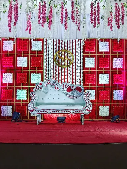 For a bold and glamorous reception, I created this stage with a striking red and white checkered backdrop and a custom gold monogram. The ornate silver sofa and hanging floral elements complete this high-impact look.