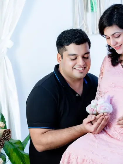 The tiny baby shoes are a perfect prop to symbolize the little one on the way. This couple shares a smile while holding the shoes near the baby bump.