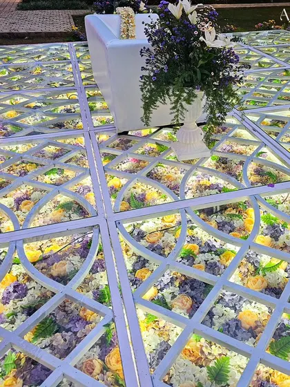 A close-up of the LED-lit glass floor filled with yellow, purple, and white flowers. This unique feature is a conversation starter and adds a major wow-factor to any event.