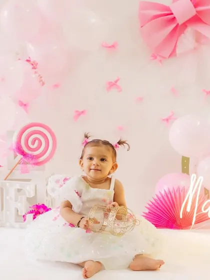 A perfect portrait of Mahhira enjoying her first birthday setup. The soft pink and white tones create a dreamy, celebratory atmosphere.