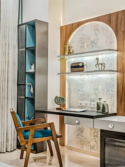 A stylish and modern study nook featuring an arched, textured back panel with integrated lighting. The combination of wood, metal, and a pop of teal in the chair creates an artistic and inspiring corner.