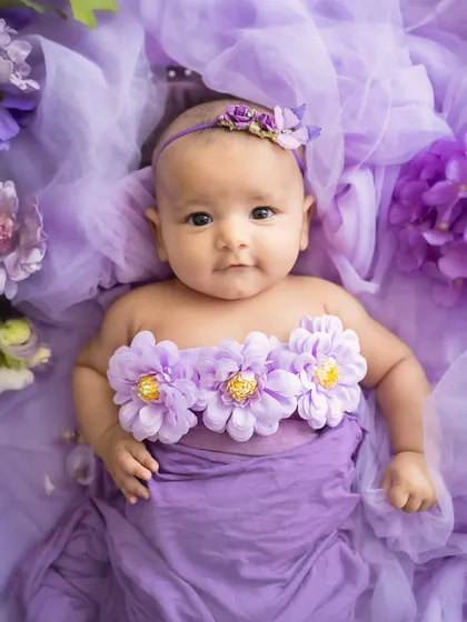 A garden of dreams. This baby girl, surrounded by a sea of purple tulle and flowers, looks like a tiny fairy.