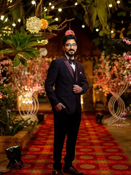 A stylish portrait of the groom at the reception. His patterned tuxedo and confident pose against the beautifully lit backdrop exude sophistication.