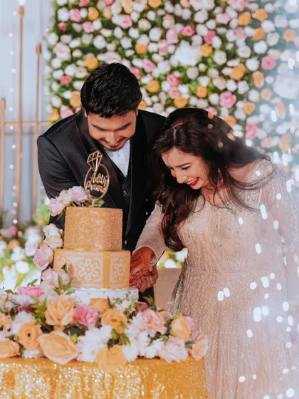 A sweet moment of the couple cutting their engagement cake, surrounded by a beautiful floral setup and the sparkle of cold pyro.
