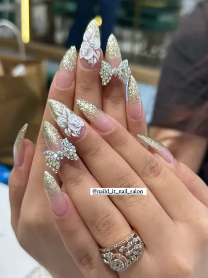 Our signature festive look, perfect for Karwachauth or your wedding day. This design features long stiletto extensions with a sparkling gold glitter base, intricate 3D acrylic roses, and fully crystallized Swarovski bows for maximum drama.