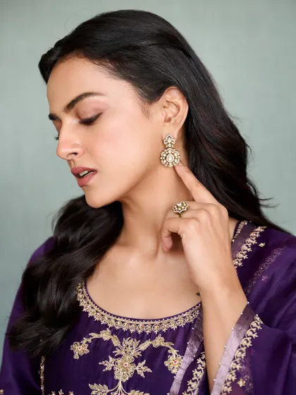 A close-up on the details of Shraddha's purple suit, showing the intricate gold embroidery and the beautiful matching earrings.