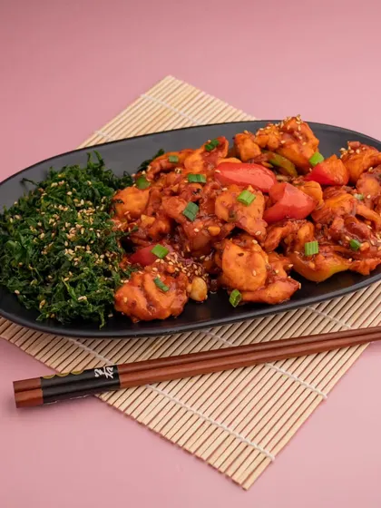 A colorful plate of sweet and sour prawns, shot against a pink background to make it stand out. This kind of vibrant, high-contrast imagery is perfect for catching attention on delivery apps.