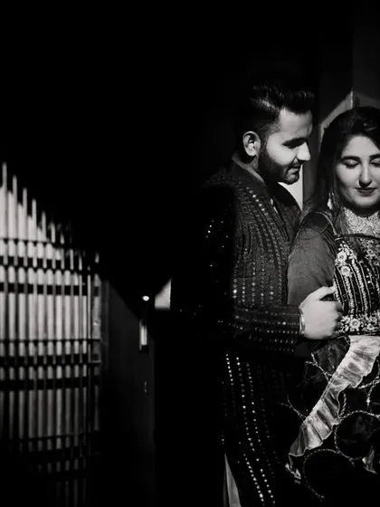 An intimate black and white portrait of the couple in a low-light setting. The shadows create a sense of privacy and romance.