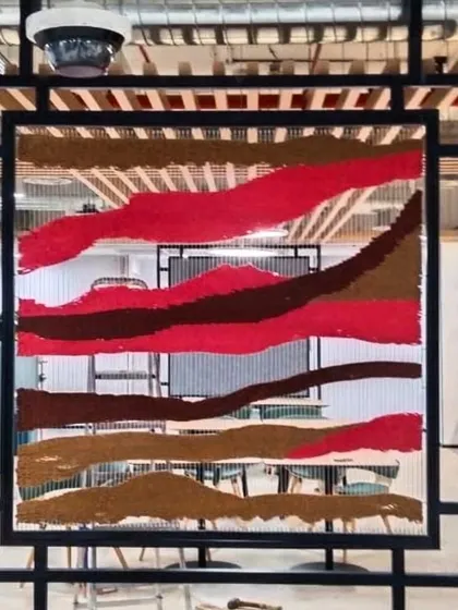 The red tapestry installed in the office space. These pieces function as both art and architecture, defining the room.