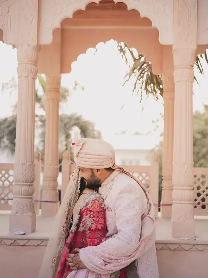 A tender moment as the groom embraces his bride under a beautiful archway. The composition frames them perfectly, creating a sense of intimacy and romance.