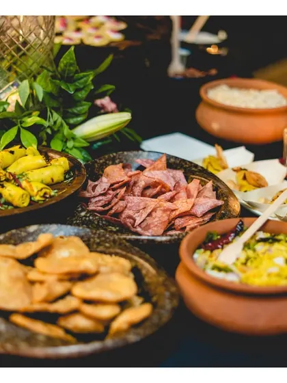 A rustic display of traditional Indian snacks, including Khandvi, Chakli, and other savoury bites, served in earthy terracotta and stone bowls.
