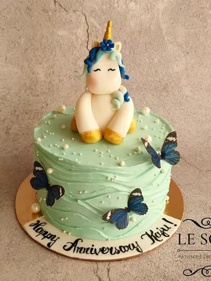 Unicorns don't always have to be pink. This half-kg Chocolate Truffle anniversary cake features a serene unicorn in a lovely teal and blue color scheme with butterfly accents.