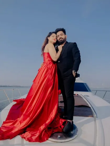 A classic portrait of the couple on the yacht. Her stunning red gown and his sharp black suit create a look of timeless elegance against the blue sea.