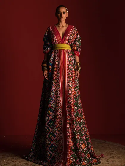 A dramatic, full-length shot of a patola saree styled into a magnificent, floor-sweeping ensemble. This high-fashion interpretation showcases the versatility of the traditional textile, transforming it into a couture statement.