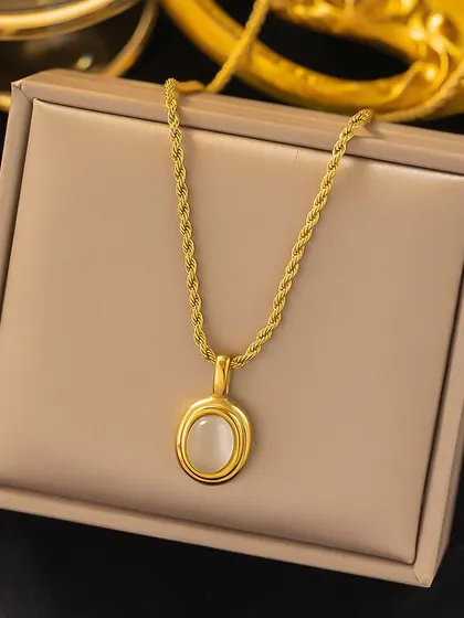 An elegant necklace featuring a white oval stone in a gold-toned setting, resting in its gift box. This piece is made from the finest materials to last for years.