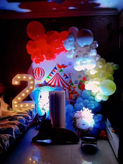 A vibrant circus-themed decoration for a 2nd birthday. This compact setup includes a circus tent backdrop, animal cutouts, and a marquee number '2', all brightly lit.
