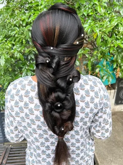 An artistic and highly creative hairstyle featuring a large, sculpted flower made from the client's own hair.