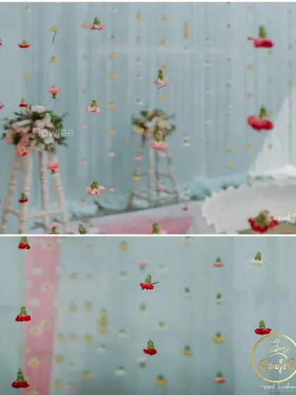 A close-up of a delicate and pretty backdrop with hanging flowers against a pastel blue curtain.