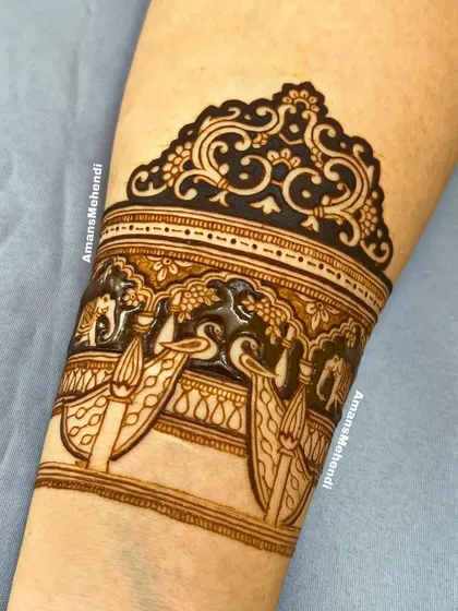 A close-up of the top part of the arm band, showing the beautiful details of the peacocks and elephants in a palace setting.