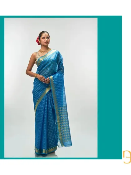 A full-length view of the Persian blue organza saree, showcasing its vibrant hue and the shimmering gold zari checks.