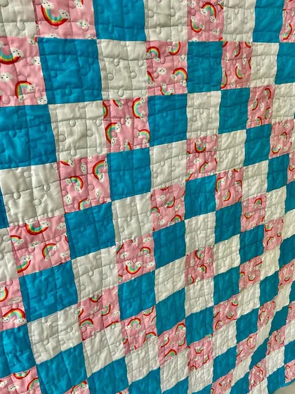 A detail shot of the "Trip Around the World" quilt, showing the cute rainbow and cloud fabric.