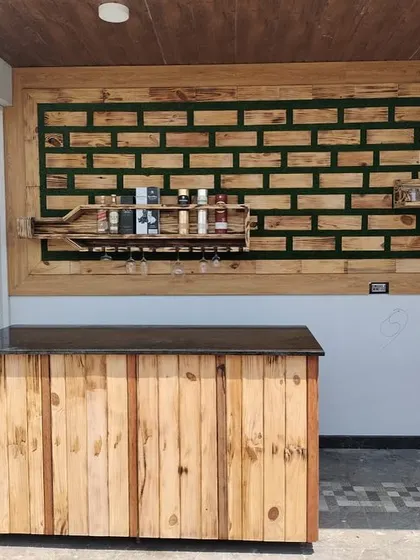 The full context of the outdoor bar area I designed. The custom wooden counter and wall art are complemented by the natural light and decorative privacy screen, making it a complete entertainment space.