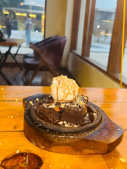 Our sizzling brownie, served hot on a wooden platter with a scoop of ice cream.