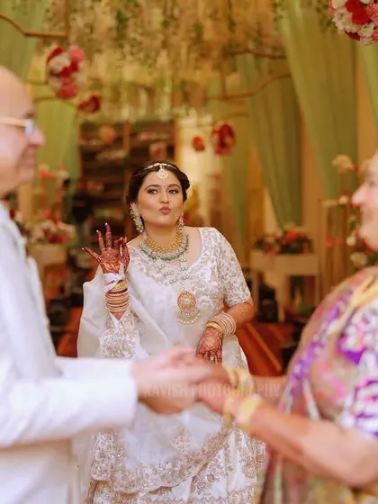 A playful, candid shot of the bride making a fun gesture towards her parents, showing the lighthearted side of family love.