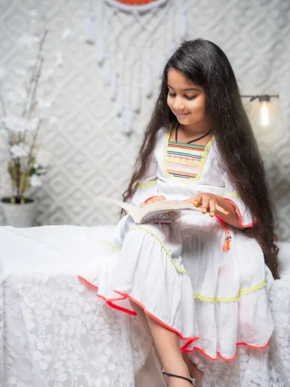 A quiet, candid moment of a young girl lost in her book. The soft lighting and simple, bright setting create a peaceful mood. This portrait shows that even the calm, everyday moments can be beautiful and full of story.