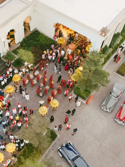 An aerial view of a grand Baraat procession arriving at the venue. This shot captures the scale and excitement of this traditional wedding celebration.