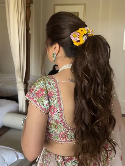 Soft beachy curls gathered into a ponytail and adorned with fresh flowers. This is a beautiful look for a daytime wedding event, with extensions making the ponytail full and lush.
