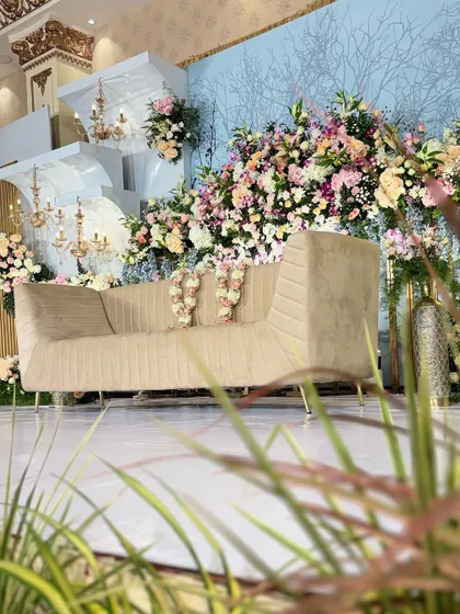 A side angle of a grand reception stage, showing the depth created by layered backdrops and abundant floral arrangements.