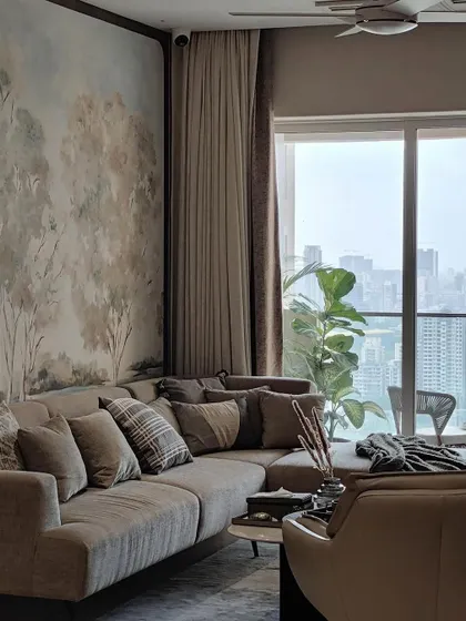 This living space, designed by Arkamine Design, features our framed artisanal wallpaper to unite the room with natural beauty. The soft, painterly treescape creates a harmonious backdrop for the custom sectional sofa, blending the interior with the cityscape beyond.