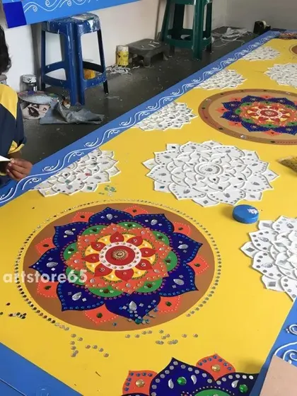 An artist from our team applying clay work to a large panel. This raised line work is a key feature of Lippan art, creating the borders and patterns where mirrors will be embedded.