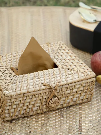 A woven tissue box holder shown in a picnic setting. This piece is perfect for keeping napkins handy outdoors or as a decorative cover in your home, blending seamlessly with natural surroundings.