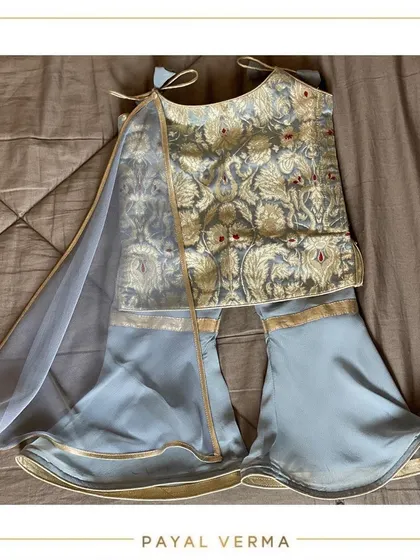 A flat-lay of the blue and gold gharara set, showcasing the beautiful fabric and the tie-shoulder details. We can customize these traditional outfits in various colors and fabrics for your little one.