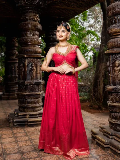 This full-length shot shows the grandeur of the red lehenga and the antique jewellery set against a temple-like backdrop. It’s a perfect combination for a majestic bridal portrait.