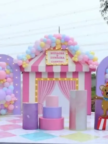 A pastel carnival theme is a whimsical and fun choice for a birthday party. This large outdoor setup includes a ticket booth, a rainbow arch, and a Ferris wheel prop.