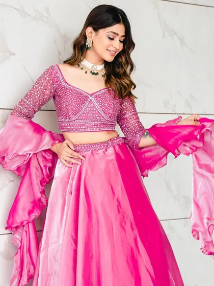 A close-up of the rose pink lehenga, highlighting the detailed blouse and the playful, flowing ruffled sleeves. It's a perfect blend of glamour and fun.