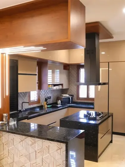 A beautiful island kitchen from an individual apartment in Velachery. The design features a combination of wood and beige tones, a black granite countertop, and a stylish wooden ceiling element.