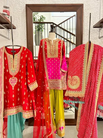 A vibrant display of festive suits in bright reds and yellows. The mix of bandhani dupattas and embroidered kurtas showcases the variety of traditional crafts available in my collection.