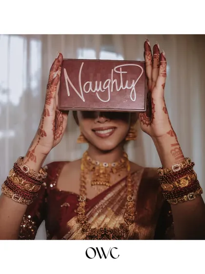 A fun and playful bridal portrait, with the bride hiding behind a "Naughty" sign, showing her fun personality.