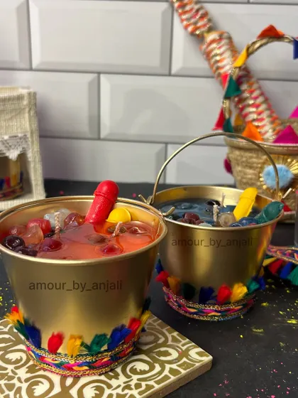 Another angle of the Holi bucket candles, showing the festive details like the colorful handle and wax pichkari. They are designed to bring the fun of Holi indoors.